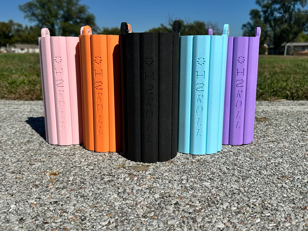 Five sleeves side by side on gravel: blush, orange, black, icy blue and lilac.
